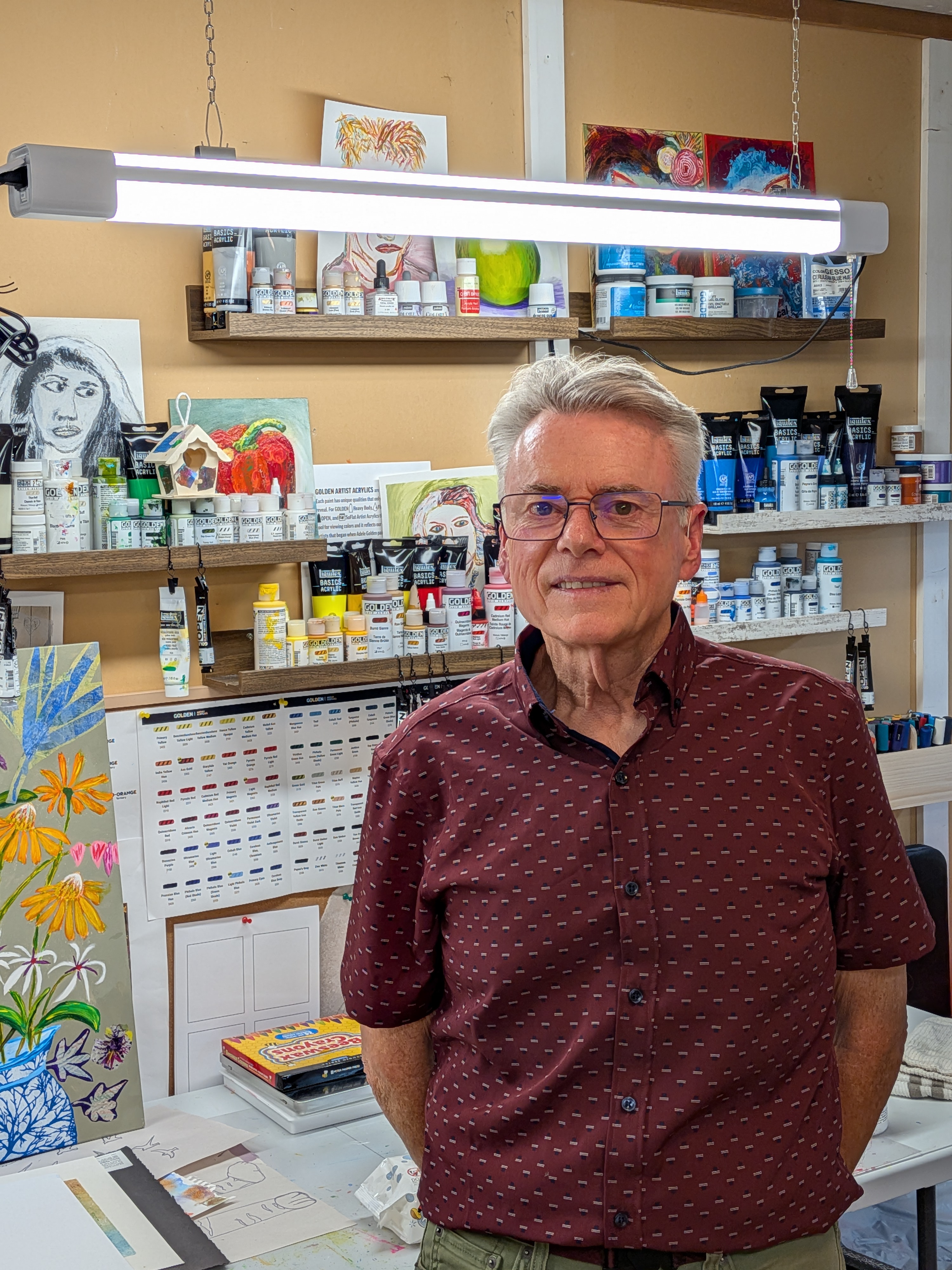 Portrait of Richard Rempel standing in his Saanich studio with a collage painting behind him